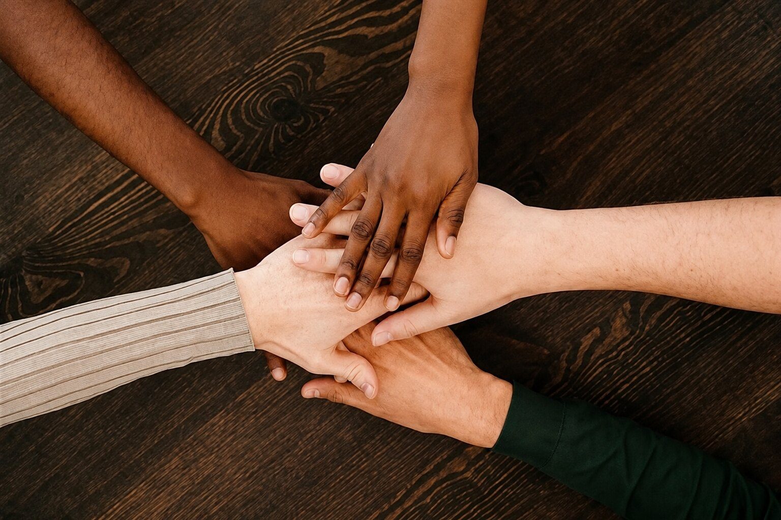 A diverse group of people placing their hands together in support