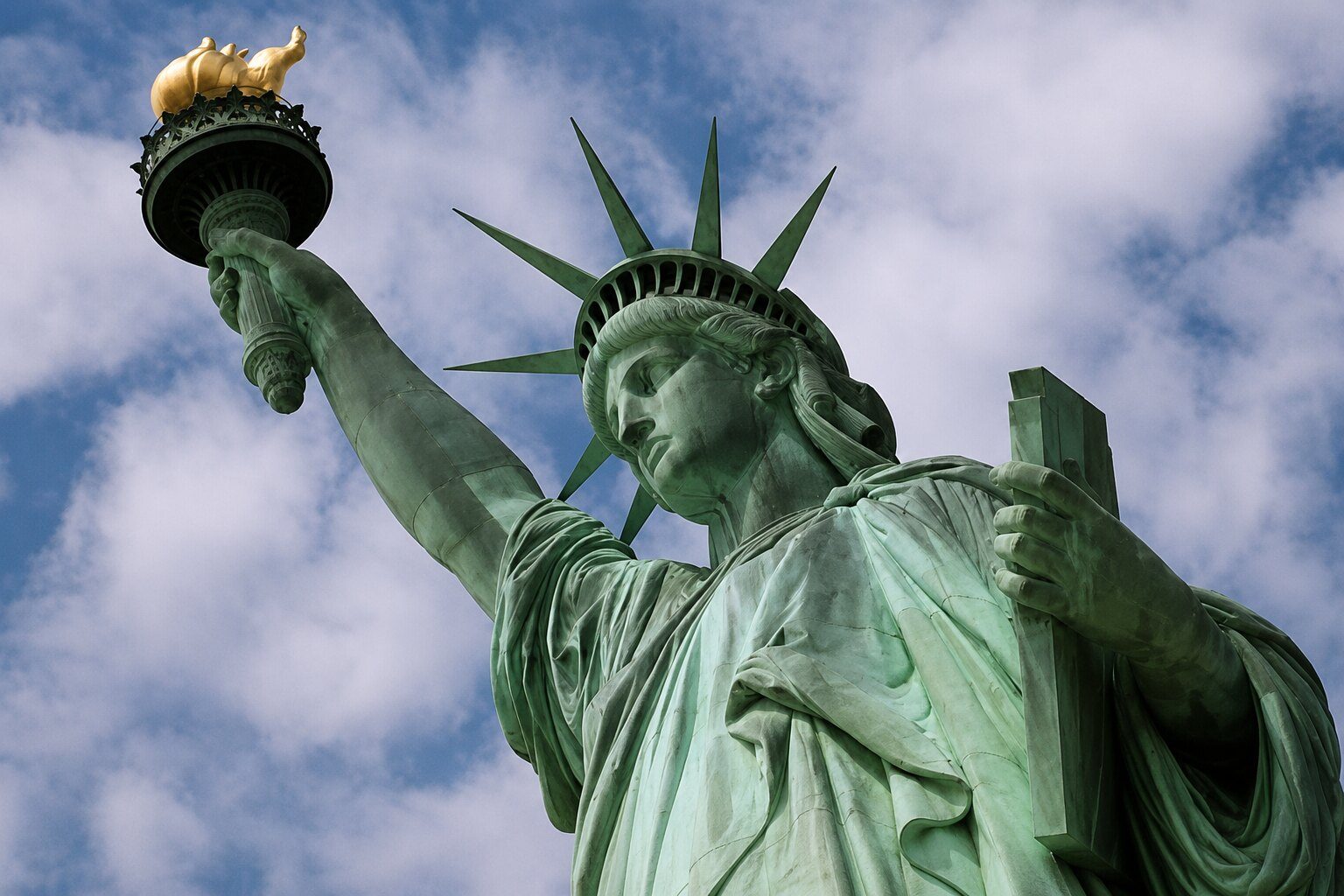 The Statue of Liberty holding her torch beneath a cloudy sky