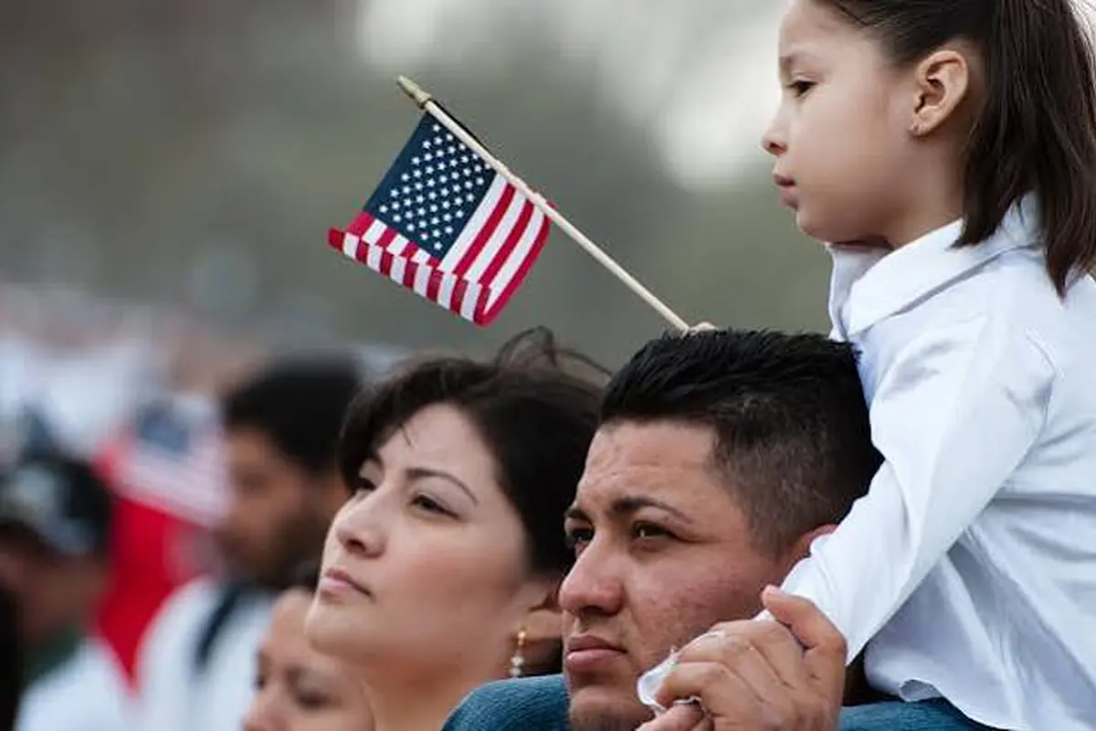 Family attending an immigration event with a child holding a flag